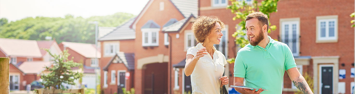 Smiling neighbors talking in front of suburban homes on a sunny day.